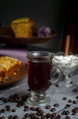 Masanın üzerinde kahve çekirdekleri ve bulanık yemek arkaplanı olan bir fincan dikey kahve.