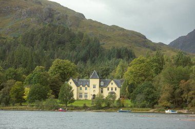 Ağaçlarla kaplı bir malikanenin manzarası. Suyun üzerinde, ağaçlarla kaplı tekneler.