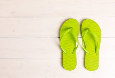 Fotokopi alanı olan beyaz ahşap zemin üzerinde yeşil parmak arası terlikler