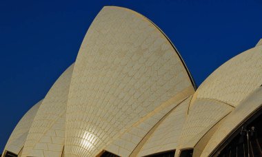Benzersiz Sydney Opera Binası 'nın mavi gökyüzüne karşı kabuk çatısı.