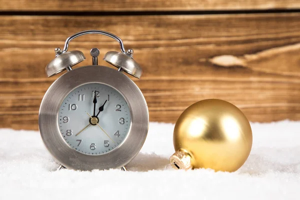 クリスマスの装飾用ボールと木製の背景を背景に雪の上の時計の閉鎖 — ストック写真