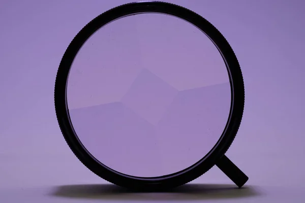 An illustration of a black magnifying glass on a purple background