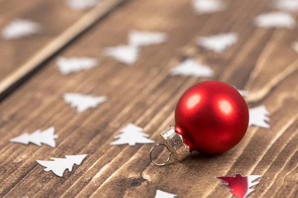 Ένα Κοντινό Πλάνο Της Κόκκινης Χριστουγεννιάτικης Μπάλας Ξύλινο Φόντο Κομφετί — Φωτογραφία Αρχείου