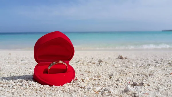 Крупный План Кольца Красной Коробке Песчаном Пляже Против Бирюзового Моря — стоковое фото