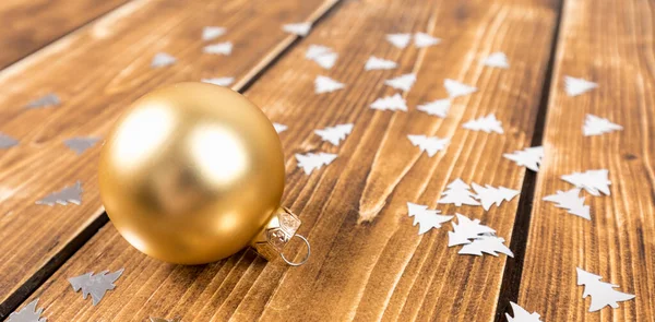 Ένα Κοντινό Πλάνο Της Χρυσής Χριστουγεννιάτικης Μπάλας Ξύλινο Φόντο Κομφετί — Φωτογραφία Αρχείου