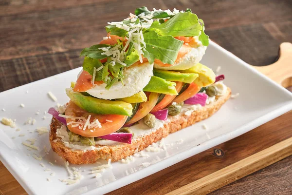 Closeup Shot Italian Bruschetta Tomatoes Avocado Poached Eggs Onions Arugula — Stock Photo, Image