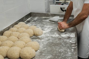 Ekmek için un kaplı hamur parçaları yapan bir fırıncının yakın çekimi.