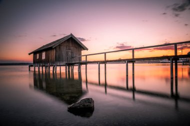 Almanya, Bavyera 'da Ammersee Gölü' nde gün batımına karşı eski bir kayıkhane.