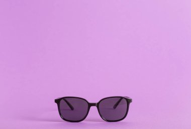 Mor arka planda bir güneş gözlüğünün yakın çekimi.