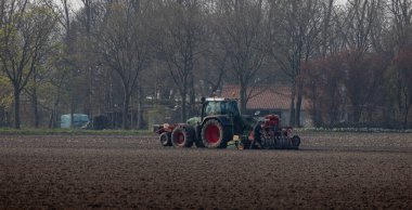 Hollanda, Nederweert 'teki bir tarım tarlasında traktörün bakımını yapan bir adamın güzel bir görüntüsü.