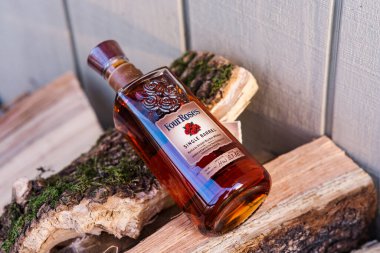 Açık havada yakacak odun yığınları üzerinde dört güllük viski şişesinin yüksek açılı çekimi.