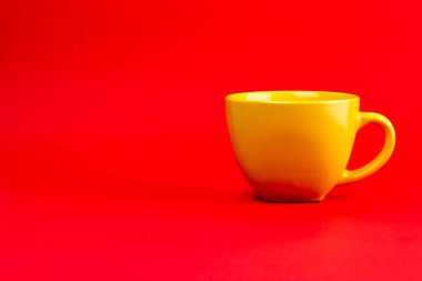 Kırmızı arkaplanda seramik sarı bir çay fincanı..