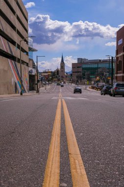 Denver, Colorado, ABD 'de mavi bulutlu bir gökyüzü olan bir kiliseye giden asfalt bir caddenin alçak açılı görüntüsü.