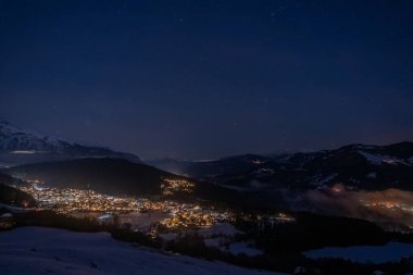 Geceleri Falera, Surselva, İsviçre 'deki karlı ev ve dağların fotoğrafı.