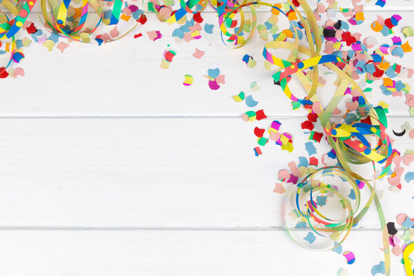 A white wood panel carnival party background with colorful confetti, streamers, and copy space