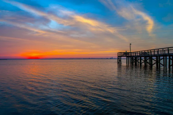 在美国阿拉巴马州莫比尔湾平静的海水中反射出一片多云的落日 — 图库照片