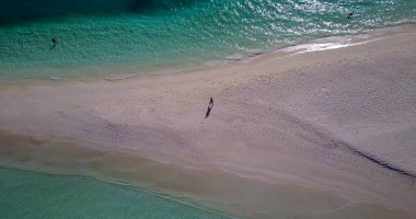 Issız bir adada yürüyen bir kadının hava görüntüsü.