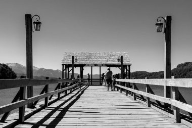 Turistlerin yaz mevsiminde ahşap bir sahil platformunda gri tonda çekilmesi