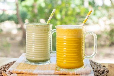 Masanın üzerinde iki bardak taze meyve püresi.