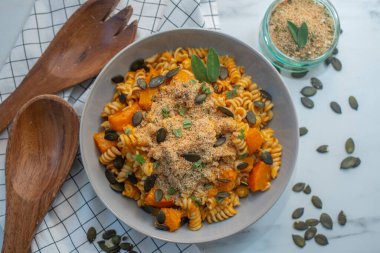 Yanında büyük ahşap çatal bıçaklar olan lezzetli bir balkabağı makarna kasesinin üst görüntüsü.