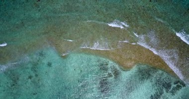 Temiz su ve sakin köpüklü dalgalarla güzel bir tropikal adanın hava aracı görüntüsü.