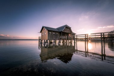 Almanya 'nın Bavyera şehrinde gün batımına karşı Ammersee Gölü üzerinde güzel bir kayıkhane manzarası