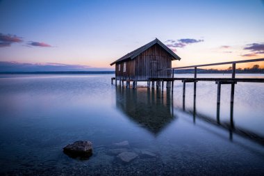 Almanya, Bavyera 'da Ammersee Gölü' nde gün batımına karşı eski bir kayıkhane.
