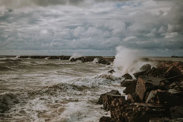 湾の美しいショットと波が曇った空の下で雨の日に岩を打つ — ストック写真