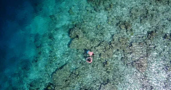 モルディブのサンゴ礁とターコイズブルーの海で泳ぐ人々のトップビュー — ストック写真