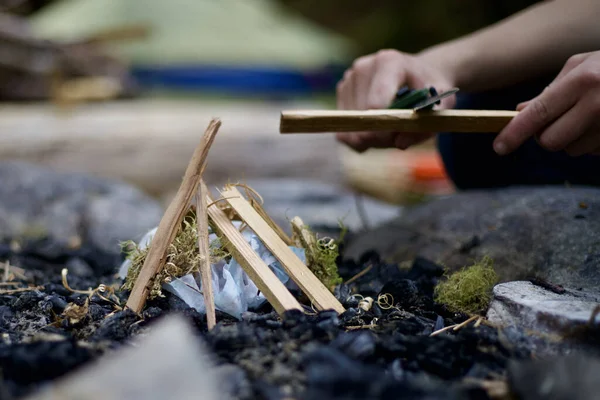 A closeup shot of a small fire begin added on to by the camper