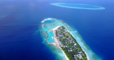 Gök mavisi bir okyanusun ortasındaki küçük bir adanın havadan çekilmiş görüntüsü.