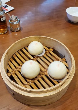 Geleneksel buhar sepetinde nilüfer tohumlu çöreklerle Dim sum 'un dikey yakın çekimi. Hong Kong.