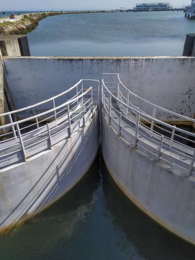 Deniz manzarasının arka planında iki kemer şekilli köprünün dikey görüntüsü.