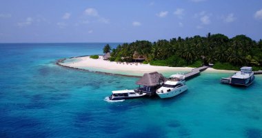 Bir adanın rıhtımına yanaşan teknelerin hava görüntüsü.