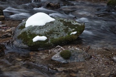 Dağ nehrinin güzel bir akışı, hızlı akan su, kayalar ve karla.