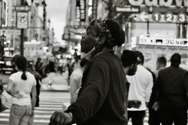 Yoğun bir caddede duran bir adamın siyah beyaz görüntüsü.