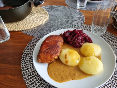 Ördekli patates ve beyaz tabakta kırmızı lahana.