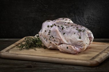 Raw Heritage tavuğunun manyetik yakın çekim çekimi ahşap bir tahtanın üzerinde biberiye ile fırına hazır.