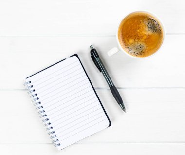 Beyaz ahşap arka planda kağıt ve kalemle bir kahve fincanının üst görüntüsü.
