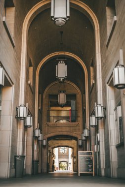 Tarihi bir şehir koleji yemek salonunun hizalı duvar lambalarıyla düşük açılı bir görüntüsü.