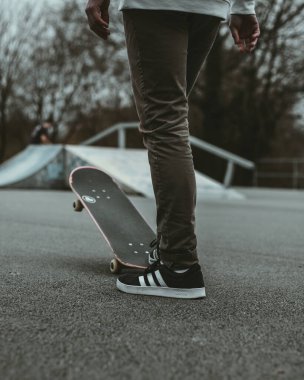 Kaykaya binen ve kaykay yapmaya hazırlanan bir adamın dikey görüntüsü..