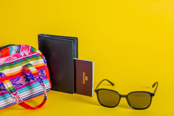 Крупный план проездного документа, солнцезащитных очков и сумочки, изолированных на желтом фоне - концепция путешествия