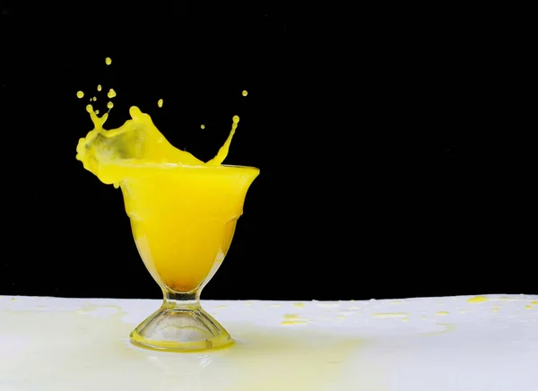 Una Bebida Naranja Fresca Salpicando Vaso Sobre Fondo Negro Aislado — Foto de Stock