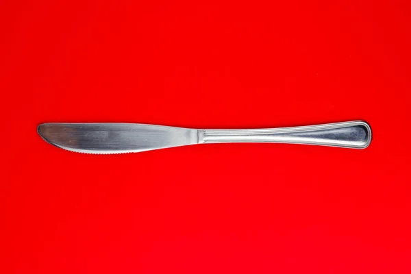 Parlak Kırmızı Arka Planda Gümüş Bir Tereyağı Bıçağının Üst Görüntüsü — Stok fotoğraf