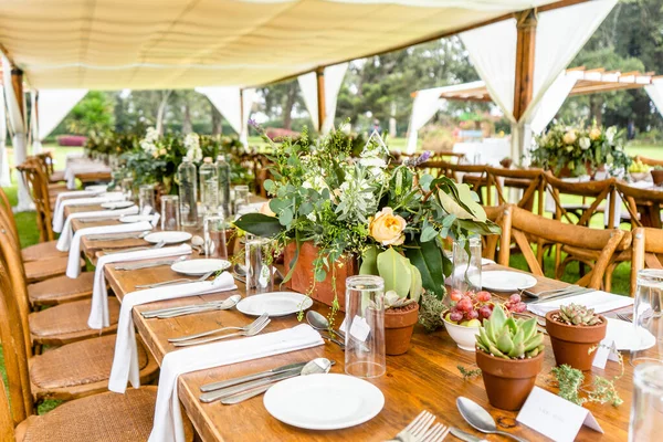 Düzenlenmiş ahşap masaları olan bir açık hava düğün yeri.