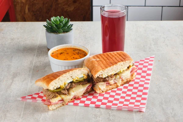 Een Cubaanse Sandwich Een Geruite Servet Naast Een Kom Soep — Stockfoto