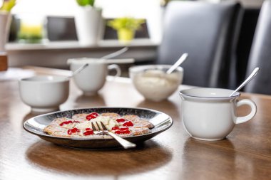 Siyah bir tabakta taze waffle ve arka planda bulanık duran ahşap bir masada kahve fincanları.