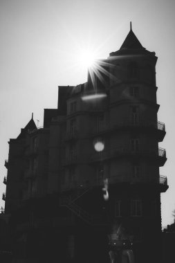 Sivri uçlu çatısı olan eski bir binanın üzerinde güneş ışınlarının dikey bir görüntüsü.