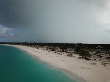 Turkuaz deniz manzarası ve kumlu sahil Gri gökyüzüne karşı.