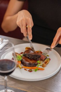 Mevsimlik sebzelerle servis edilen yavaş pişirilmiş sığır yanaklı burginyonun dikey yakın çekimi.